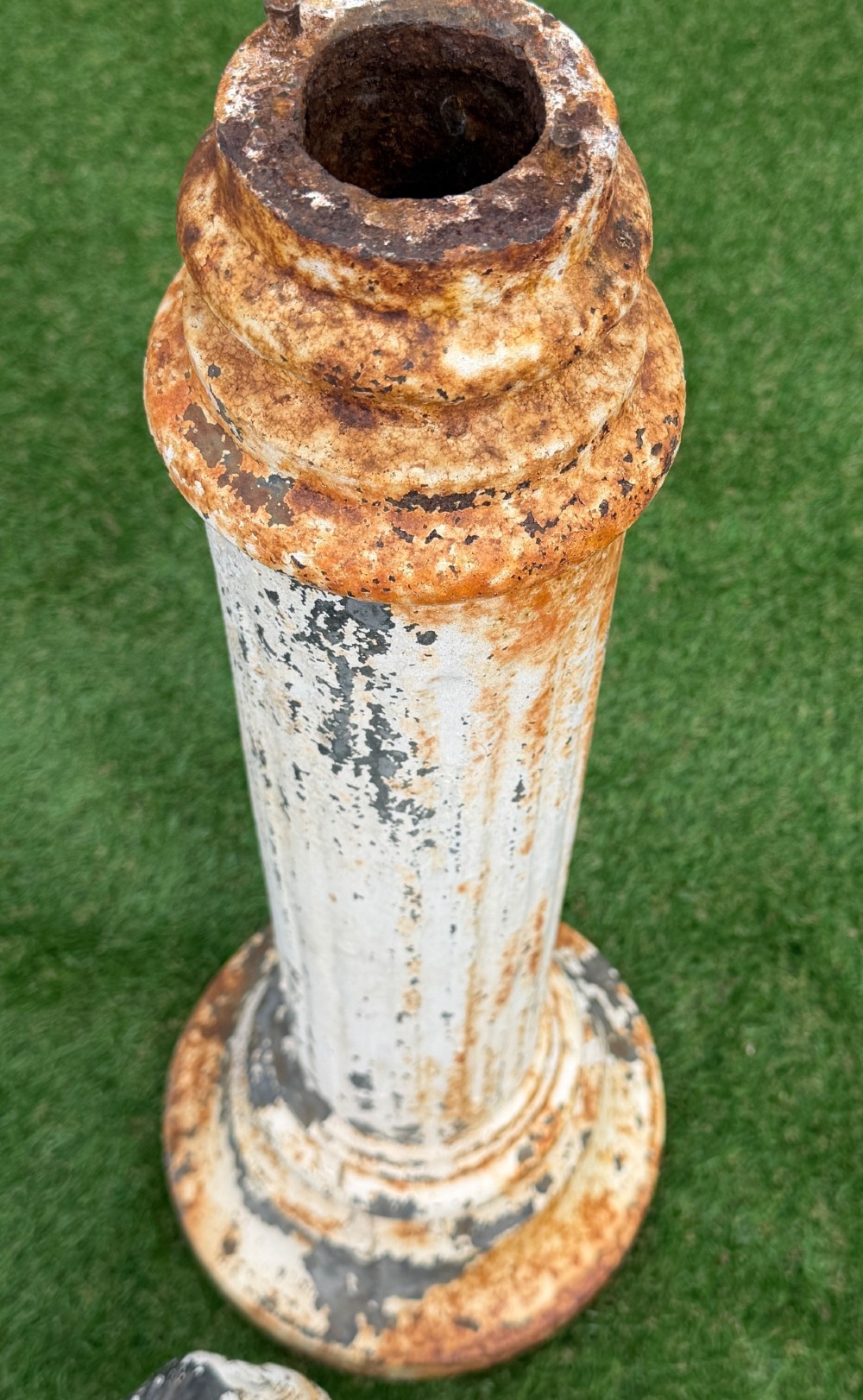 A late Victorian cast iron bird bath featuring a fluted column base and a scallop shell basin topped with a seated cherub figure, showing weathered paint and rust oxidisation. View IV
