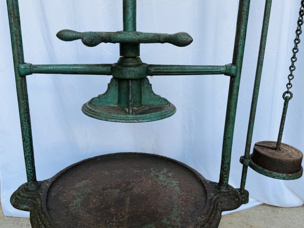 A Victorian patinated green cast iron and forged steel cheese press featuring a threaded screw mechanism, wheel handle, lever arm, chain, counterweight, and tripod legs. View III