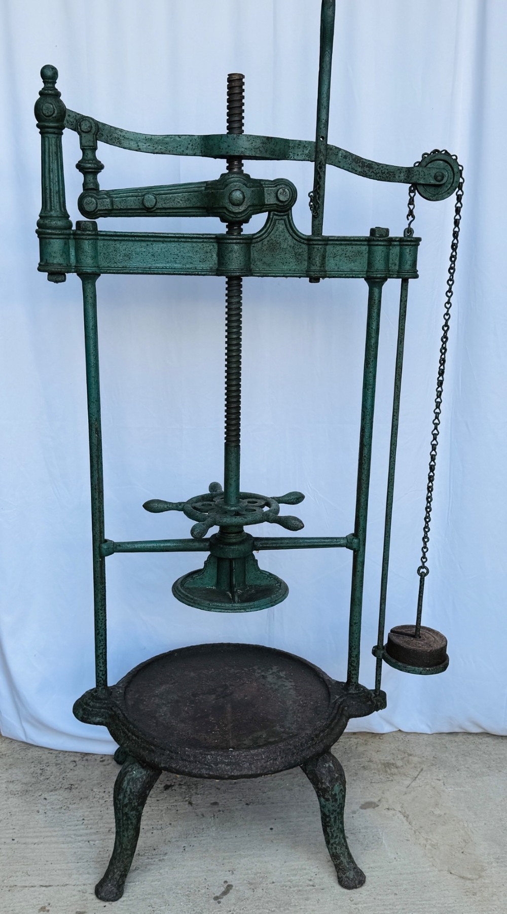 A Victorian patinated green cast iron and forged steel cheese press featuring a threaded screw mechanism, wheel handle, lever arm, chain, counterweight, and tripod legs. View V