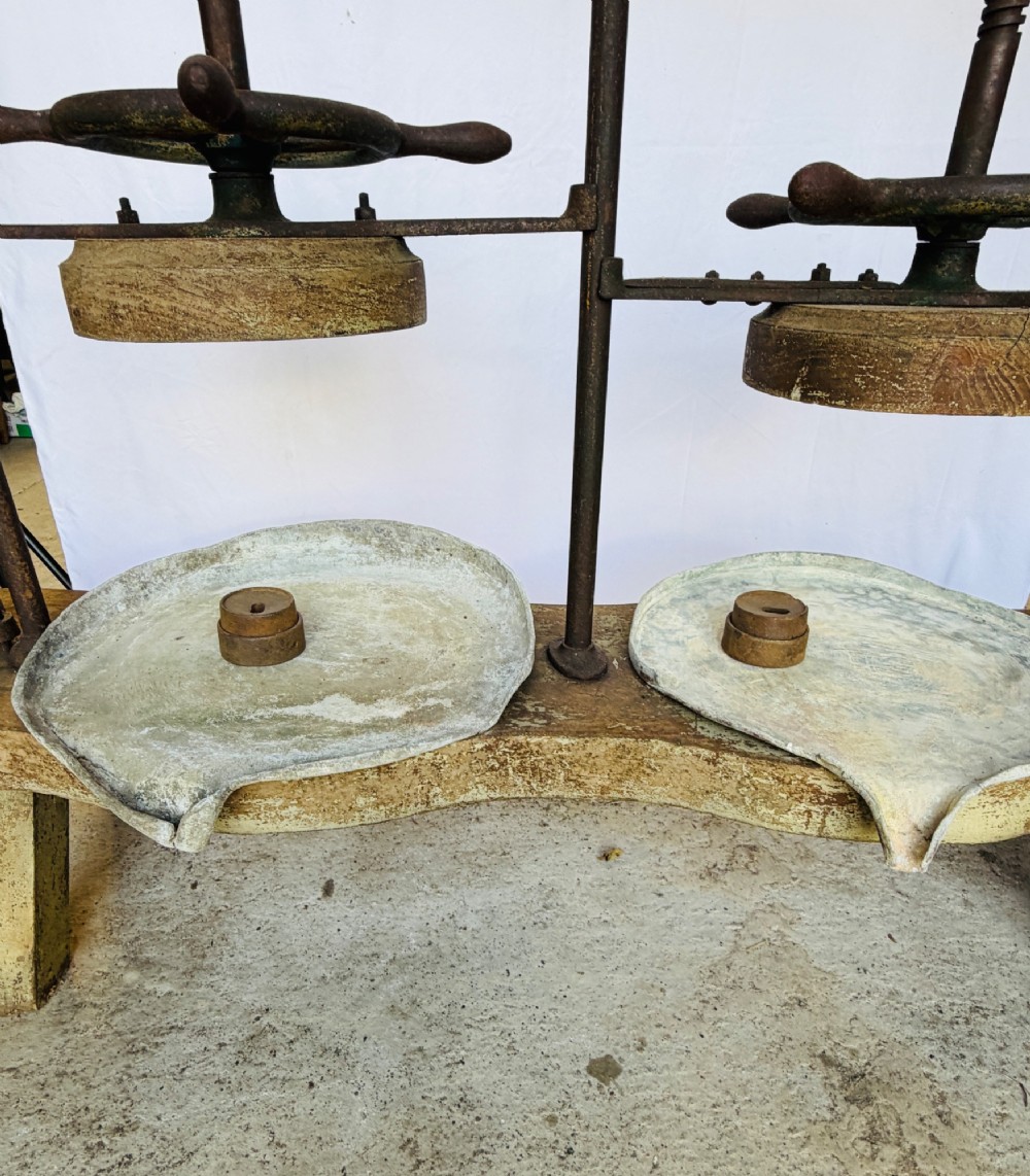 A Victorian double cheese press with a painted dark green cast-iron upper frame, twin screw spindles, and a heavy wooden base structure. View X
