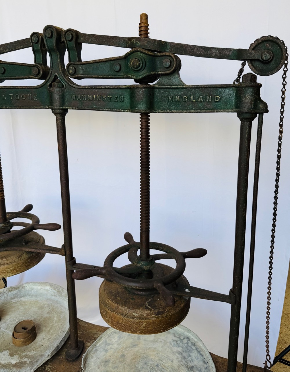 A Victorian double cheese press with a painted dark green cast-iron upper frame, twin screw spindles, and a heavy wooden base structure. View XII