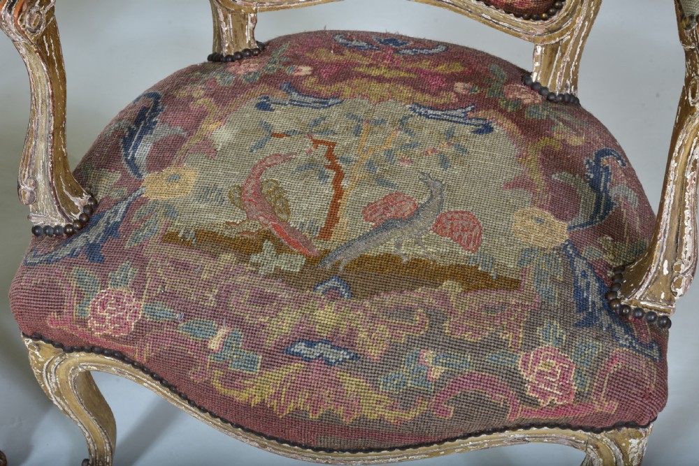 A pair of late 18th-century French painted wood fauteuil armchairs featuring curved cabriole legs and hand-stitched floral and figurative needlework upholstery. View II