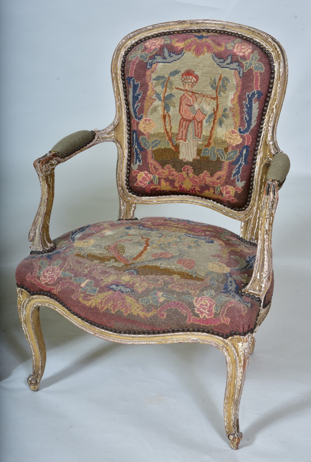 A pair of late 18th-century French painted wood fauteuil armchairs featuring curved cabriole legs and hand-stitched floral and figurative needlework upholstery. View V