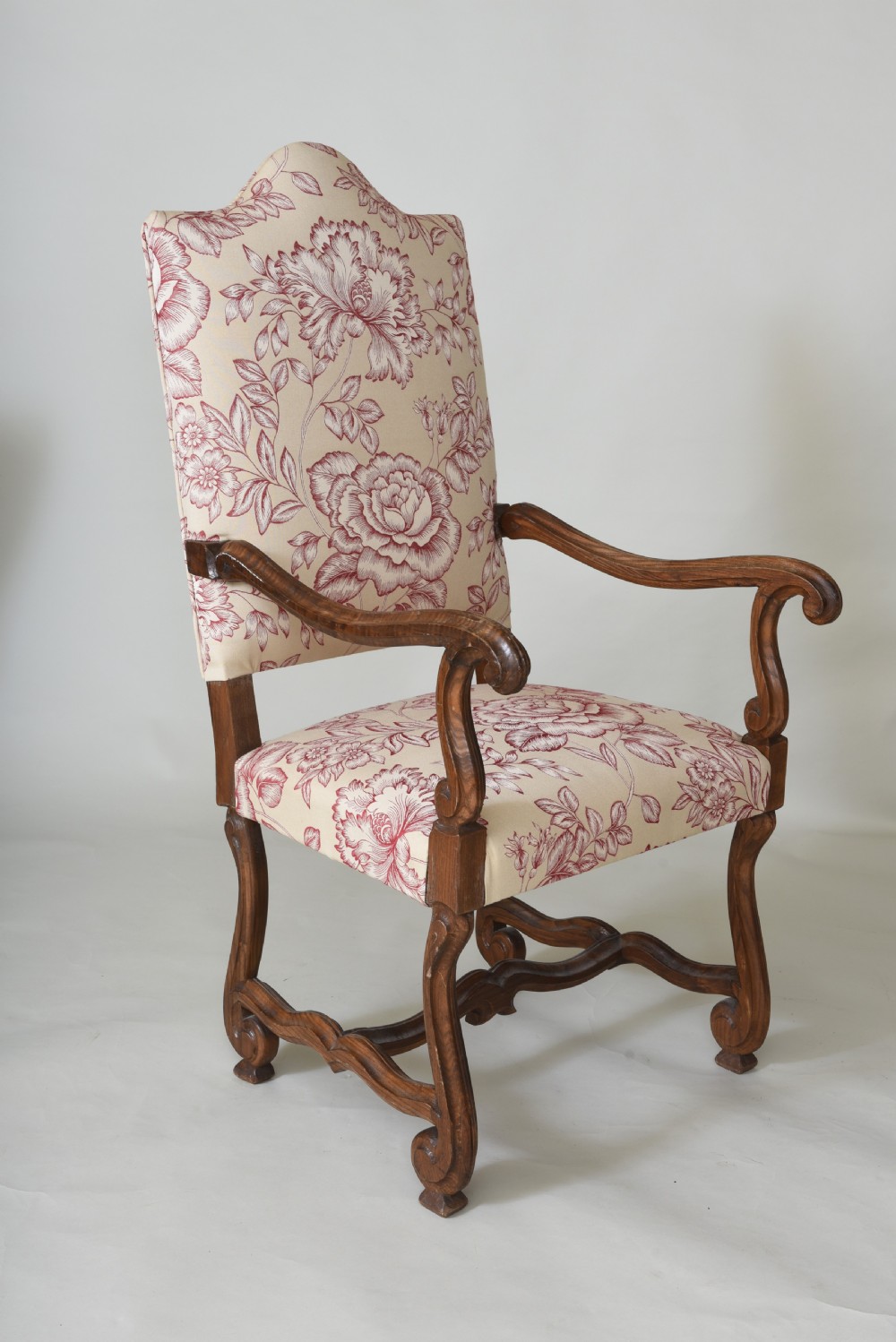 A pair of high-backed armchairs featuring carved wooden frames, curved armrests, and floral cream and red printed upholstery. View II