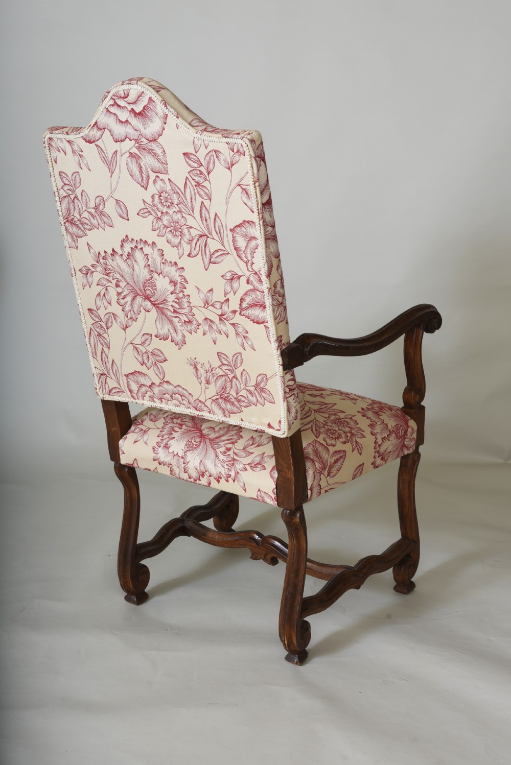A pair of high-backed armchairs featuring carved wooden frames, curved armrests, and floral cream and red printed upholstery. View III