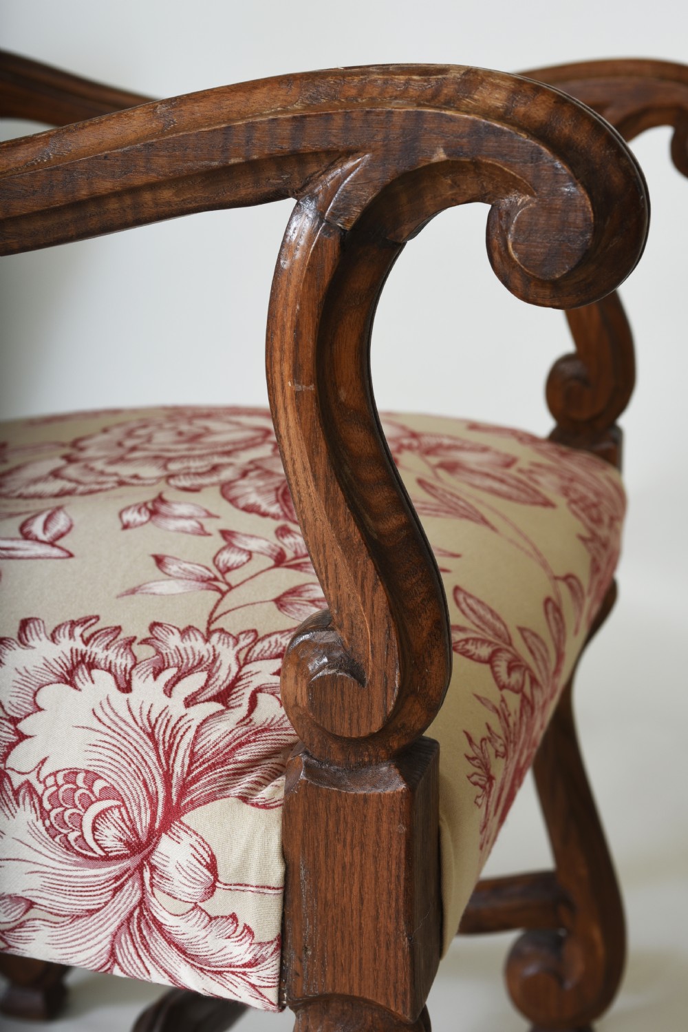 A pair of high-backed armchairs featuring carved wooden frames, curved armrests, and floral cream and red printed upholstery. View IV