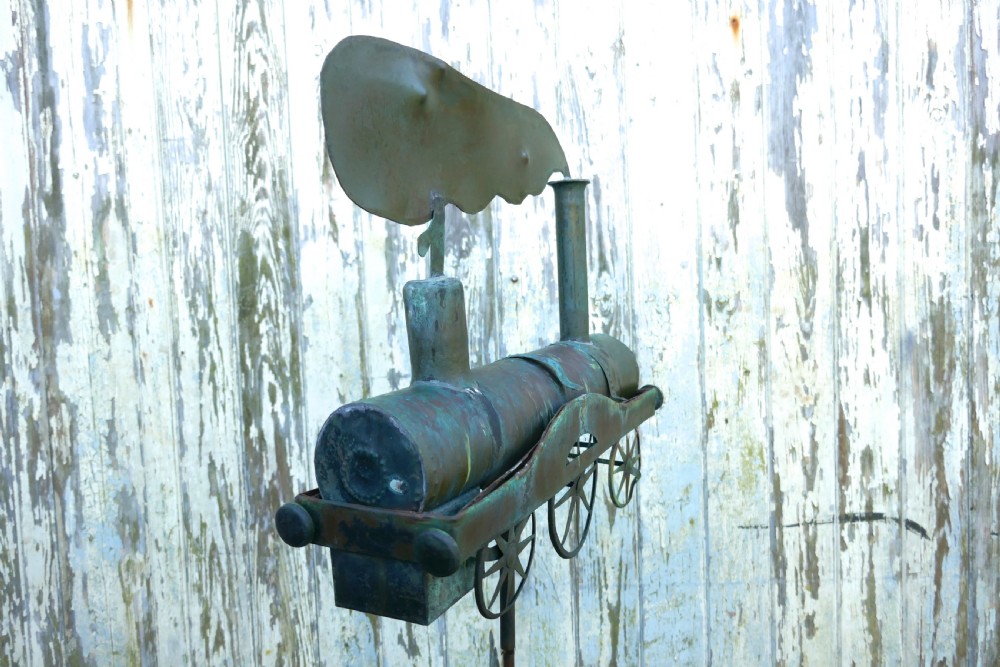 A nineteenth-century copper weather vane shaped like a steam locomotive train with verdigris patina, featuring directional cardinal points on a cast iron stand. View VIII