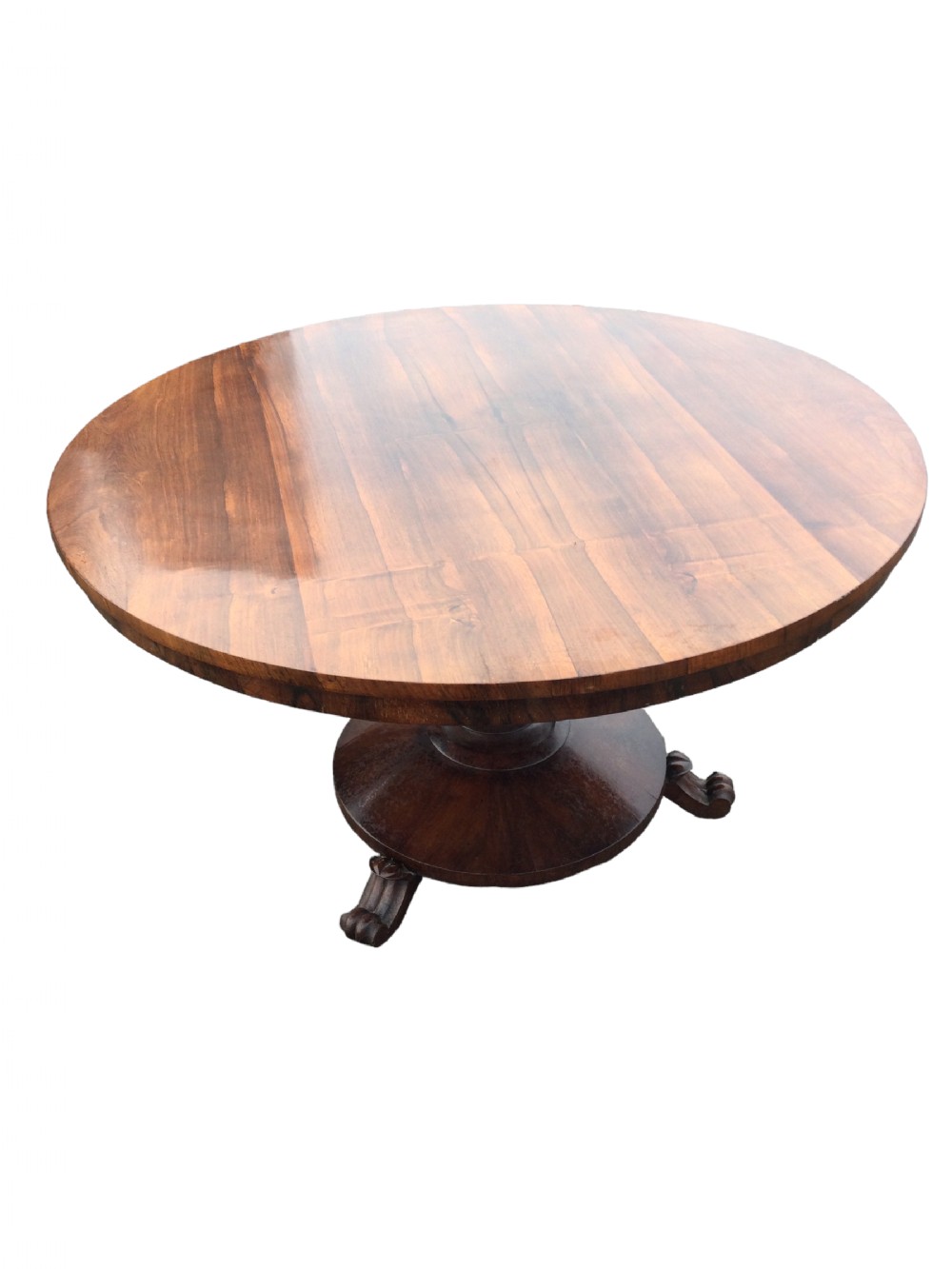 An early Victorian circular rosewood breakfast table featuring a figured timber top on a central pedestal base with carved feet.