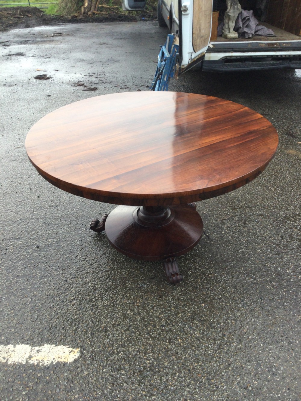 An early Victorian circular rosewood breakfast table featuring a figured timber top on a central pedestal base with carved feet. View VI