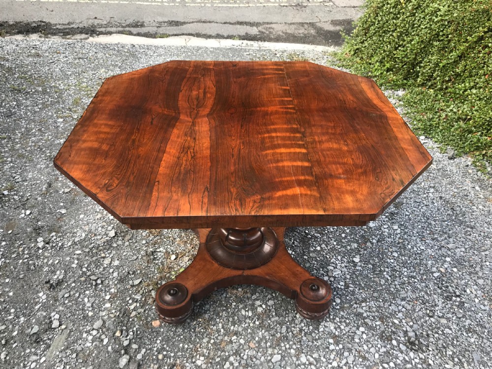 A William IV rosewood dining table featuring an octagonal top with figured veneer set upon a central turned pedestal and a triform base. View II