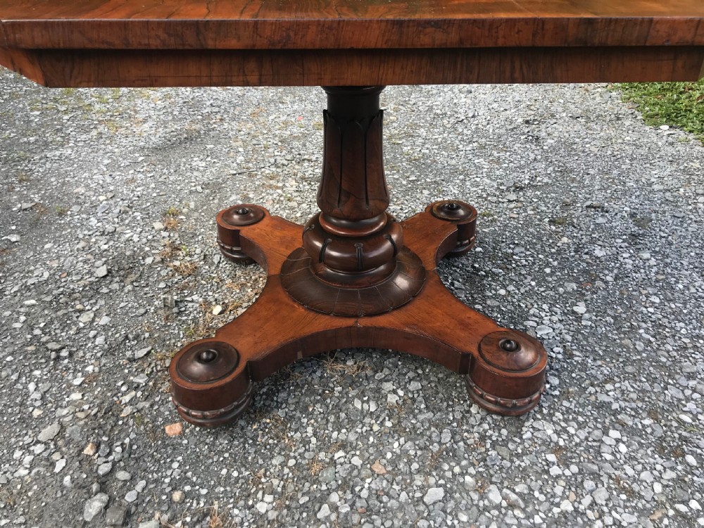 A William IV rosewood dining table featuring an octagonal top with figured veneer set upon a central turned pedestal and a triform base. View IV