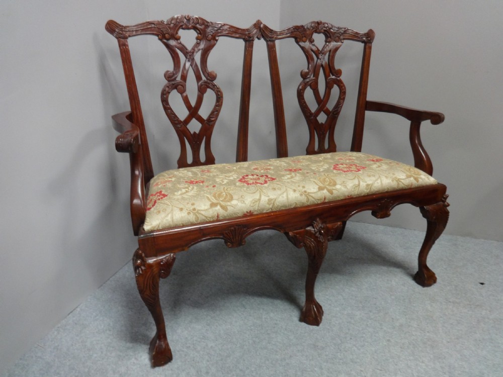 A Chippendale style mahogany double chair-back settee with pierced splats, carved cabriole legs terminating in ball-and-claw feet, and a patterned seat cushion. View III