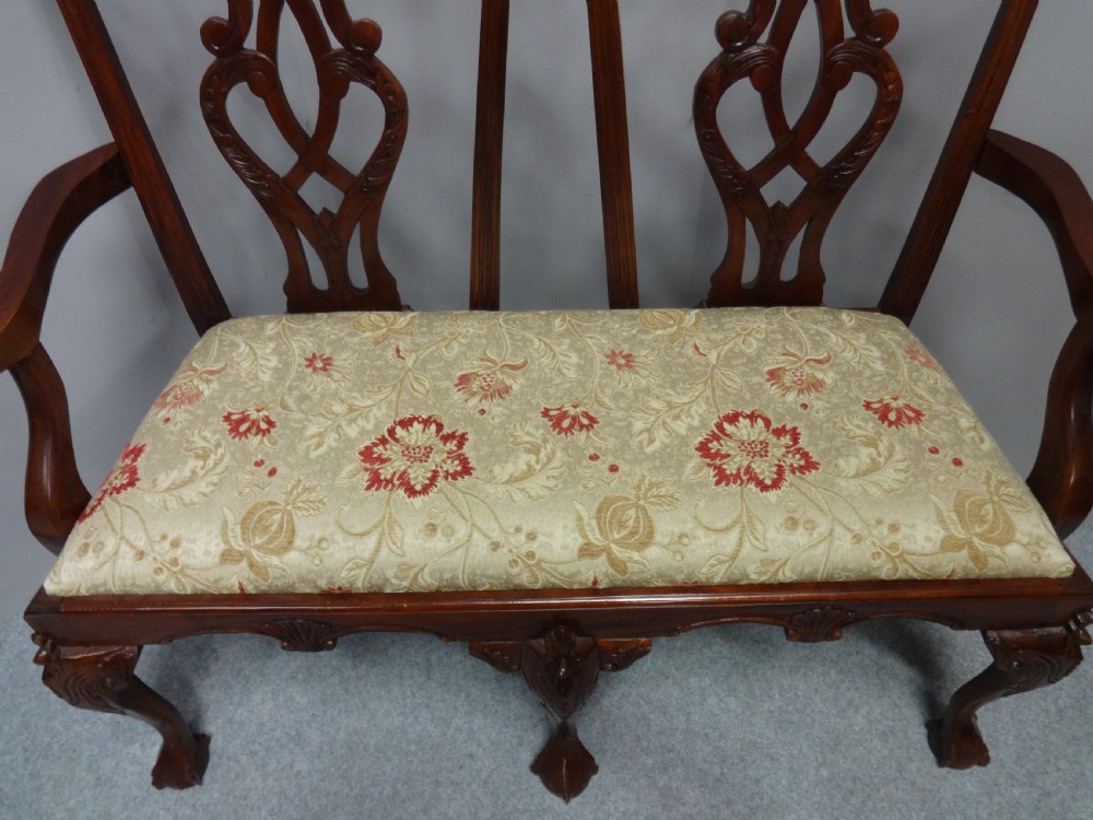 A Chippendale style mahogany double chair-back settee with pierced splats, carved cabriole legs terminating in ball-and-claw feet, and a patterned seat cushion. View VIII