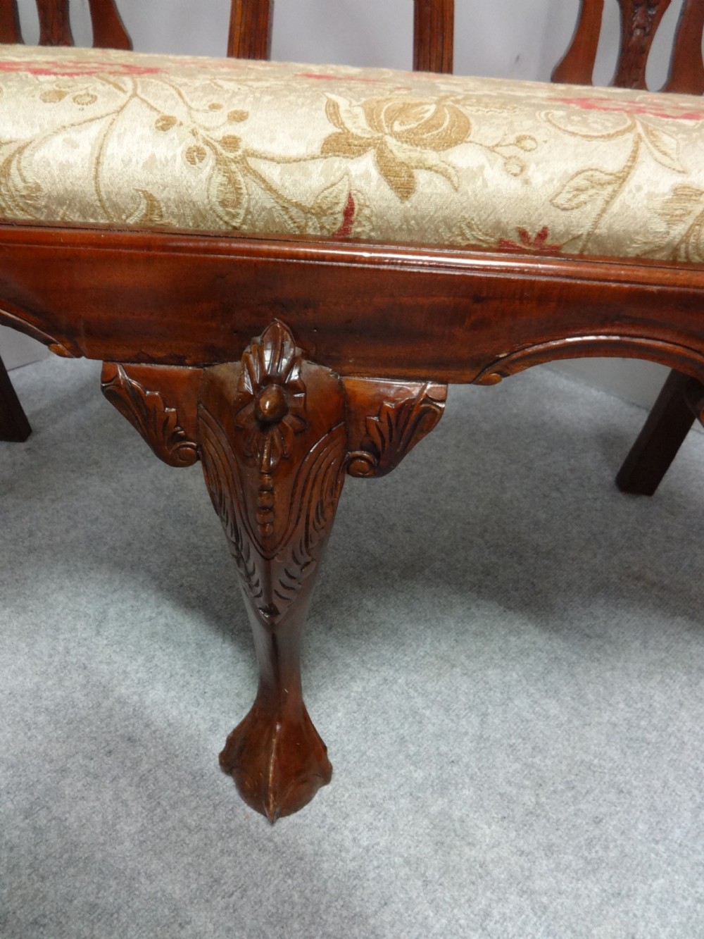 A Chippendale style mahogany double chair-back settee with pierced splats, carved cabriole legs terminating in ball-and-claw feet, and a patterned seat cushion. View IX