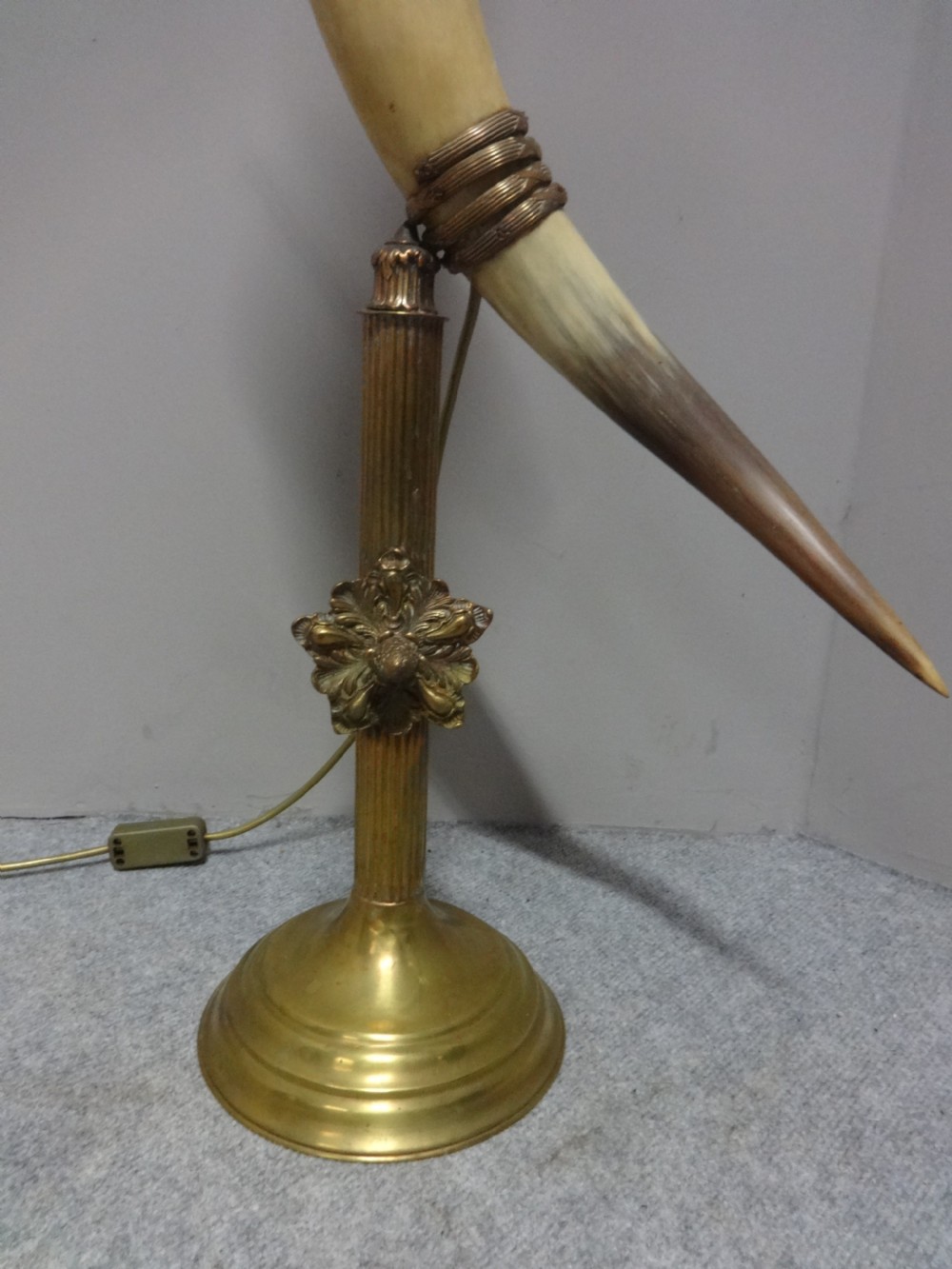 A Victorian table lamp featuring a curved natural horn stem mounted on a fluted brass pedestal base with a brass oil reservoir and clear glass chimney. View III