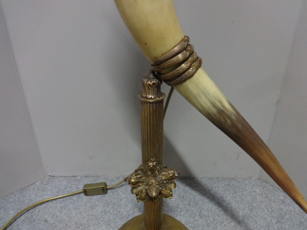 A Victorian table lamp featuring a curved natural horn stem mounted on a fluted brass pedestal base with a brass oil reservoir and clear glass chimney. View VI