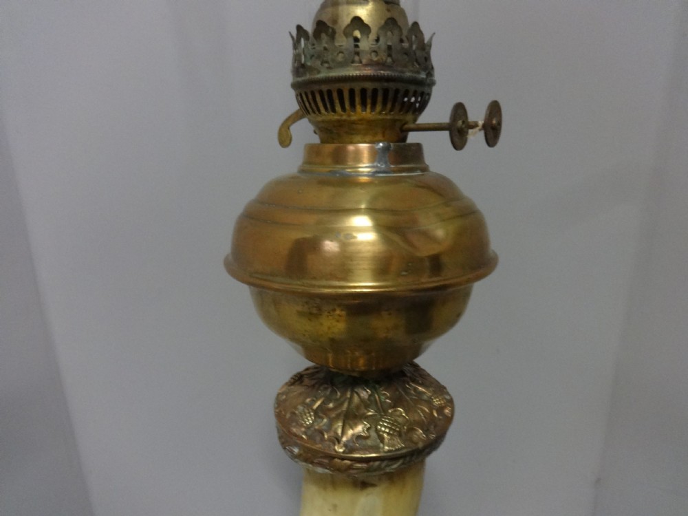 A Victorian table lamp featuring a curved natural horn stem mounted on a fluted brass pedestal base with a brass oil reservoir and clear glass chimney. View VIII