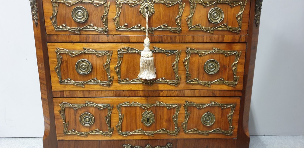 An eighteenth-century French commode chest of drawers featuring a white marble top, patterned wood veneer, and decorative gilt-bronze drawer mounts. View VII