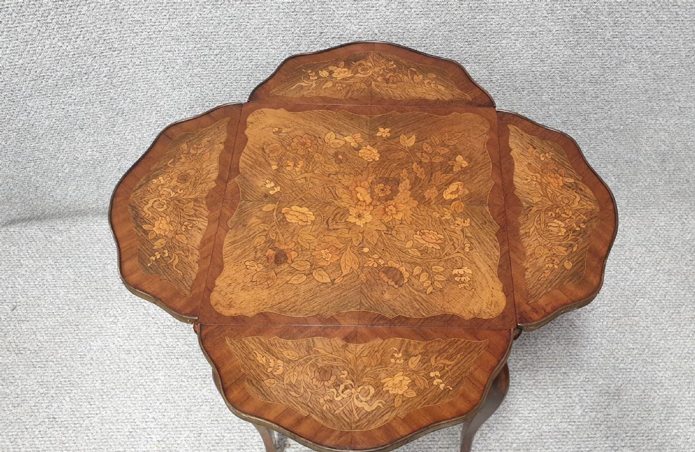 A warm brown wooden drop-flap side table featuring floral marquetry inlay, slender cabriole legs, and brass foot mounts. View III