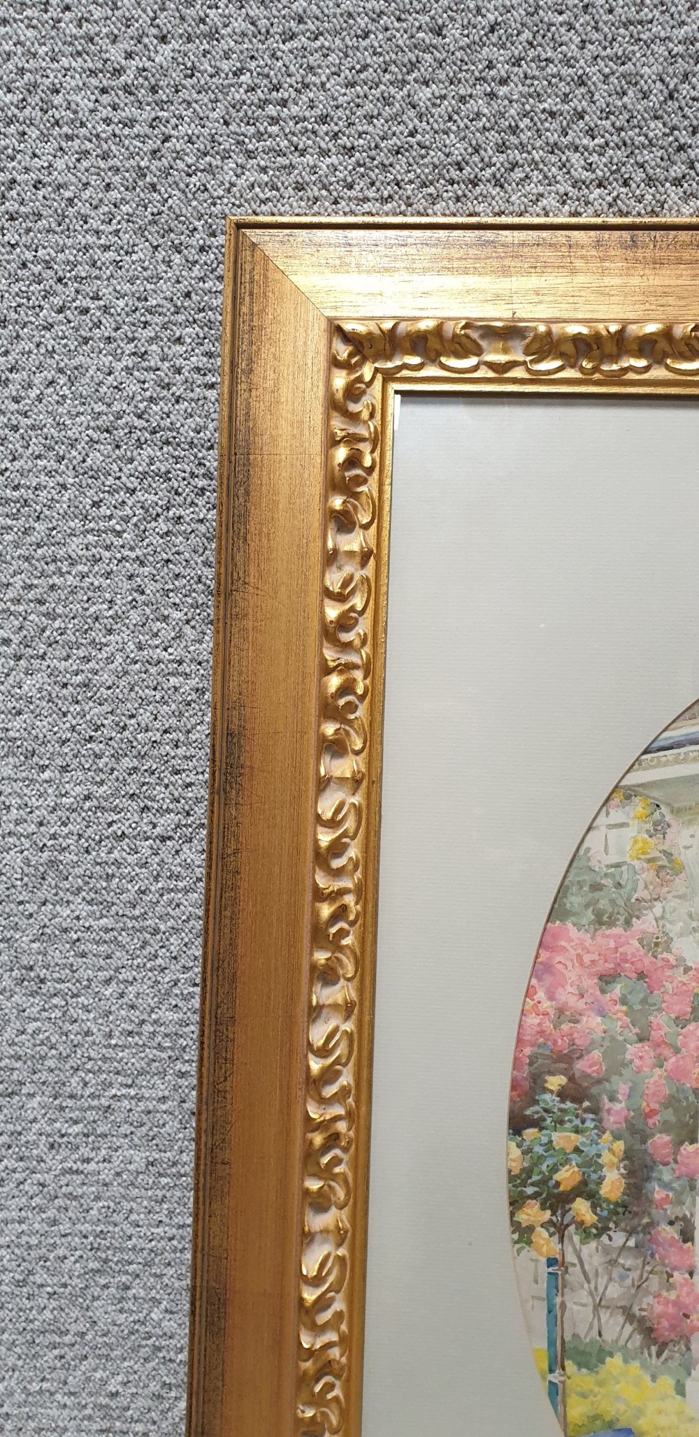 A gilt-framed watercolour painting by Arthur H. Buckland depicting a cupid standing at a cottage doorway surrounded by roses within an oval mount. View V