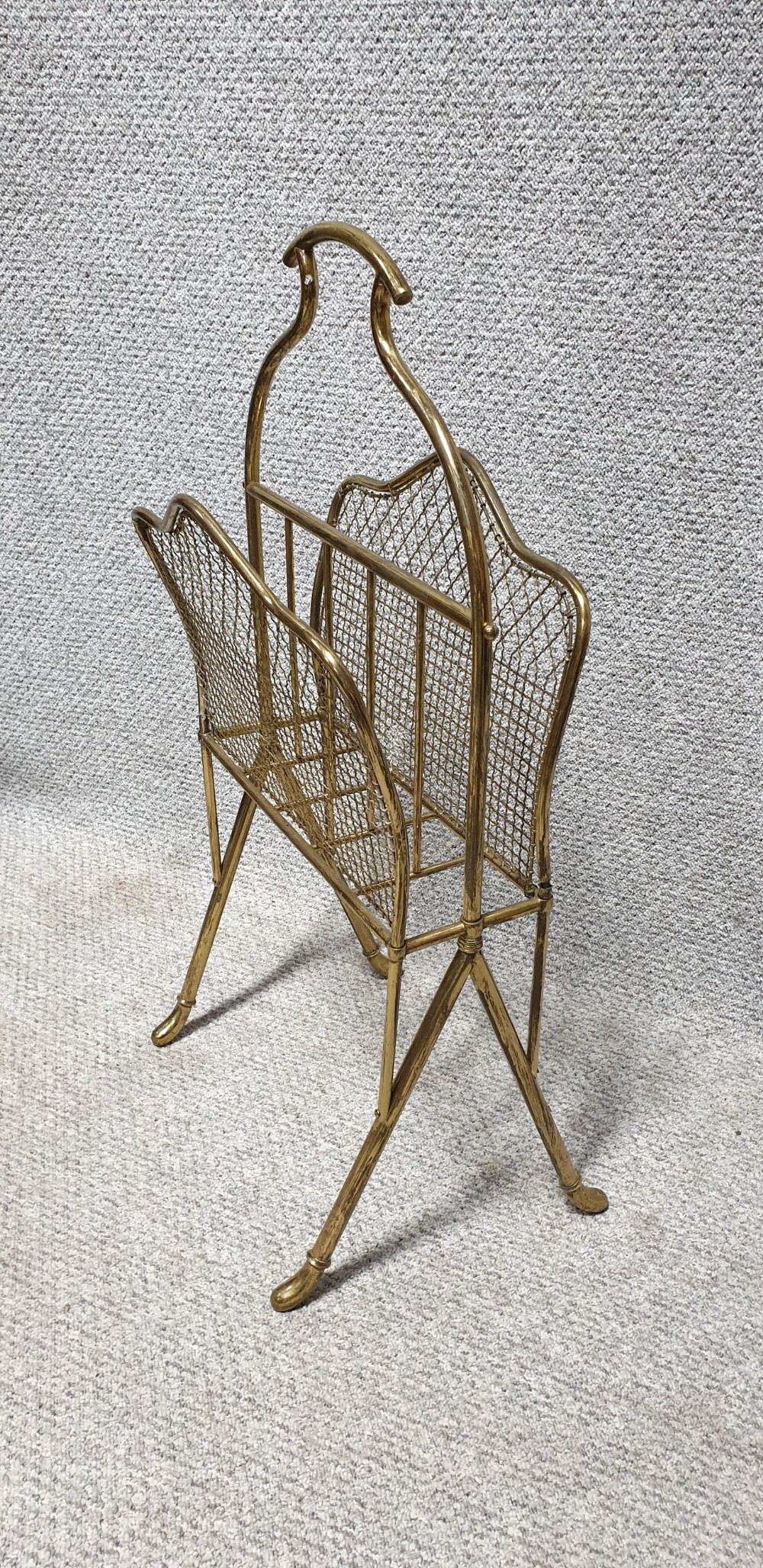 An Edwardian brass magazine rack featuring a tubular carrying handle, wire mesh sides with a central divider, and splayed legs. View III