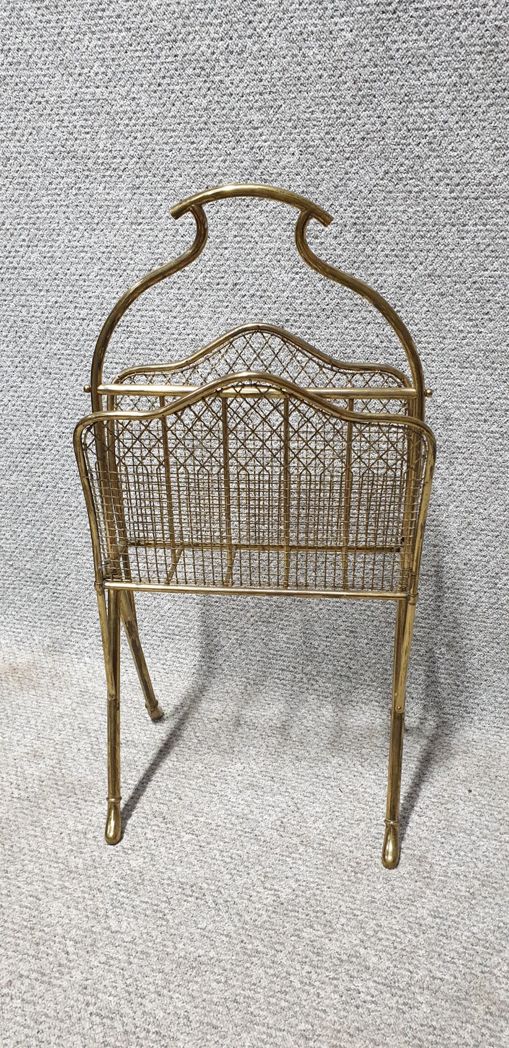 An Edwardian brass magazine rack featuring a tubular carrying handle, wire mesh sides with a central divider, and splayed legs. View IV