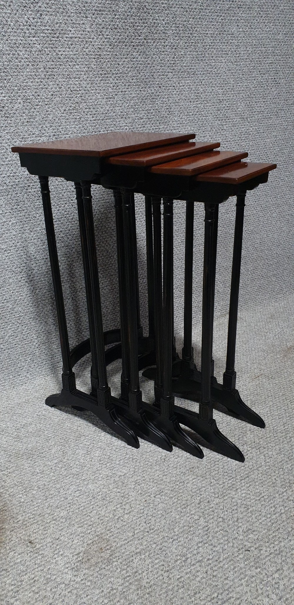 A set of four graduated mahogany nesting tables featuring rectangular tops, slender turned legs, and trestle feet.