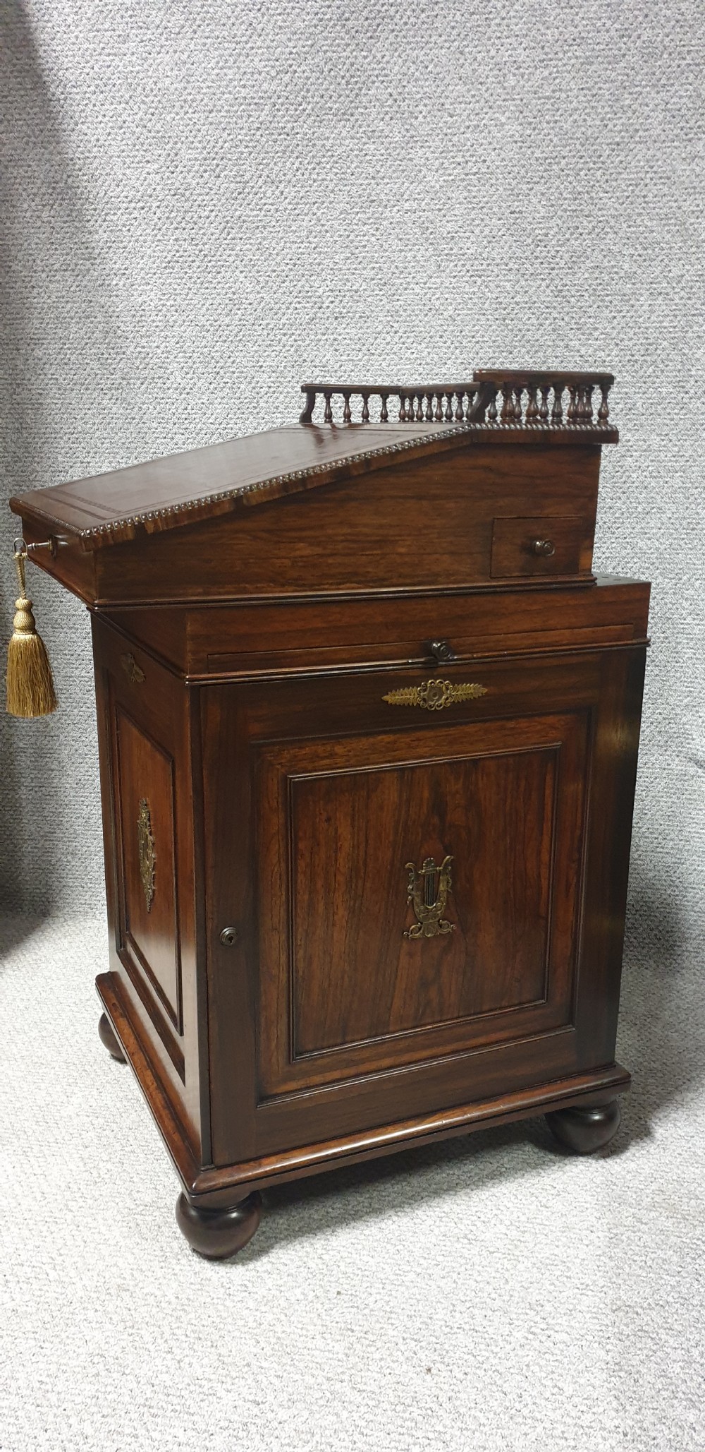 A Regency rosewood Davenport desk with a slanted leather writing slope, brass decorative mount, side drawers, and turned bun feet. View III