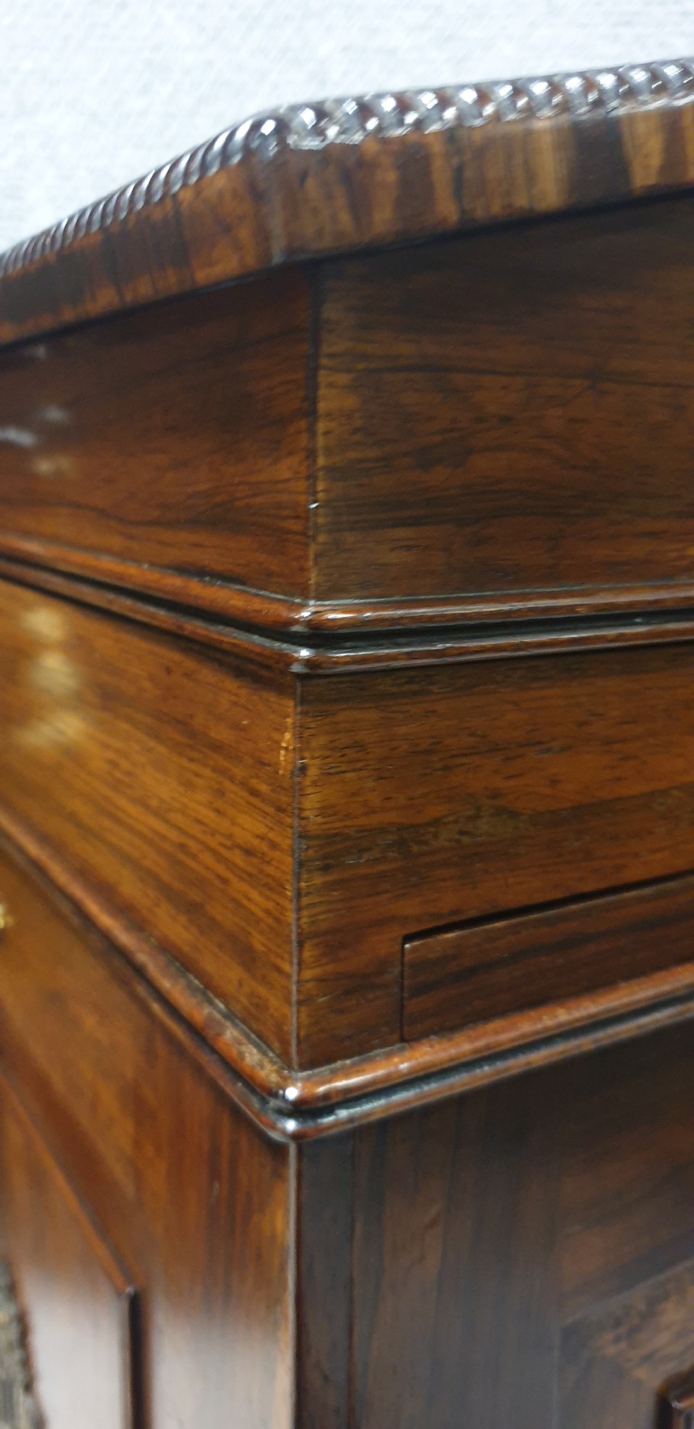A Regency rosewood Davenport desk with a slanted leather writing slope, brass decorative mount, side drawers, and turned bun feet. View V