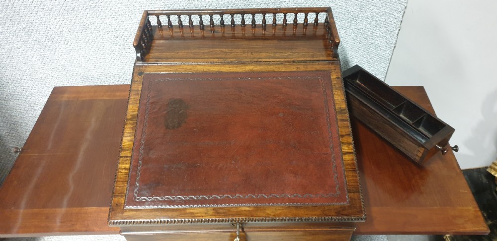 A Regency rosewood Davenport desk with a slanted leather writing slope, brass decorative mount, side drawers, and turned bun feet. View VIII
