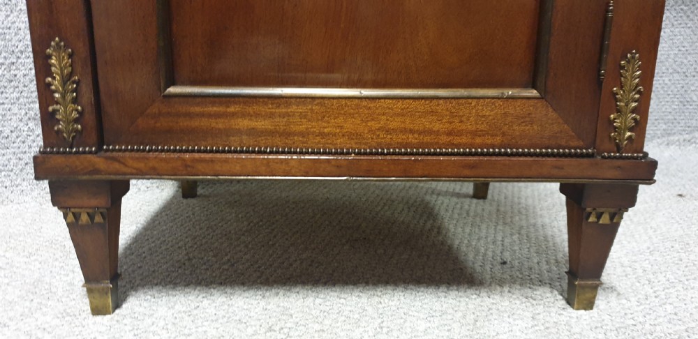 A mahogany side cabinet featuring gilt bronze mounts, a single top drawer over a cupboard door with a central laurel wreath, raised on square tapered legs. View III