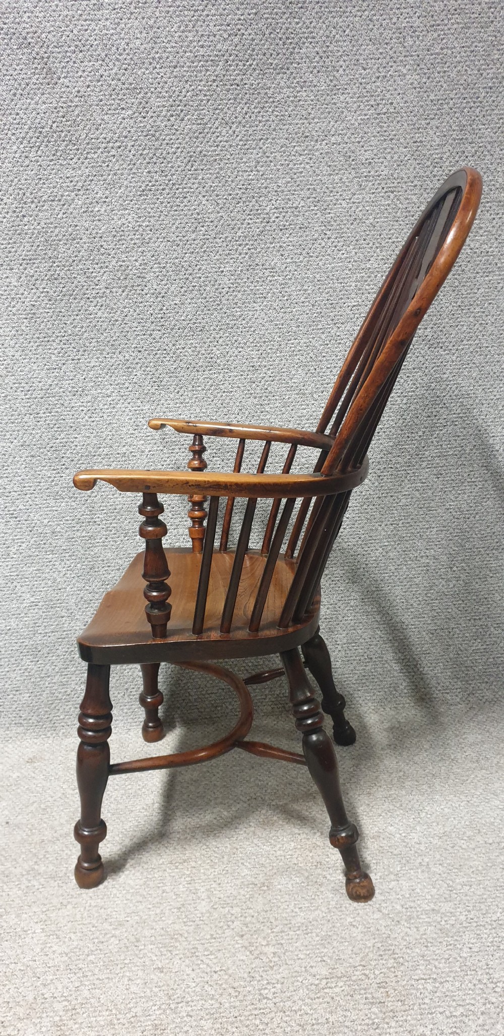 An antique yew wood Windsor armchair featuring a hoop back with vertical spindles, a decorative pierced central splat, a contoured seat, and turned legs. View V