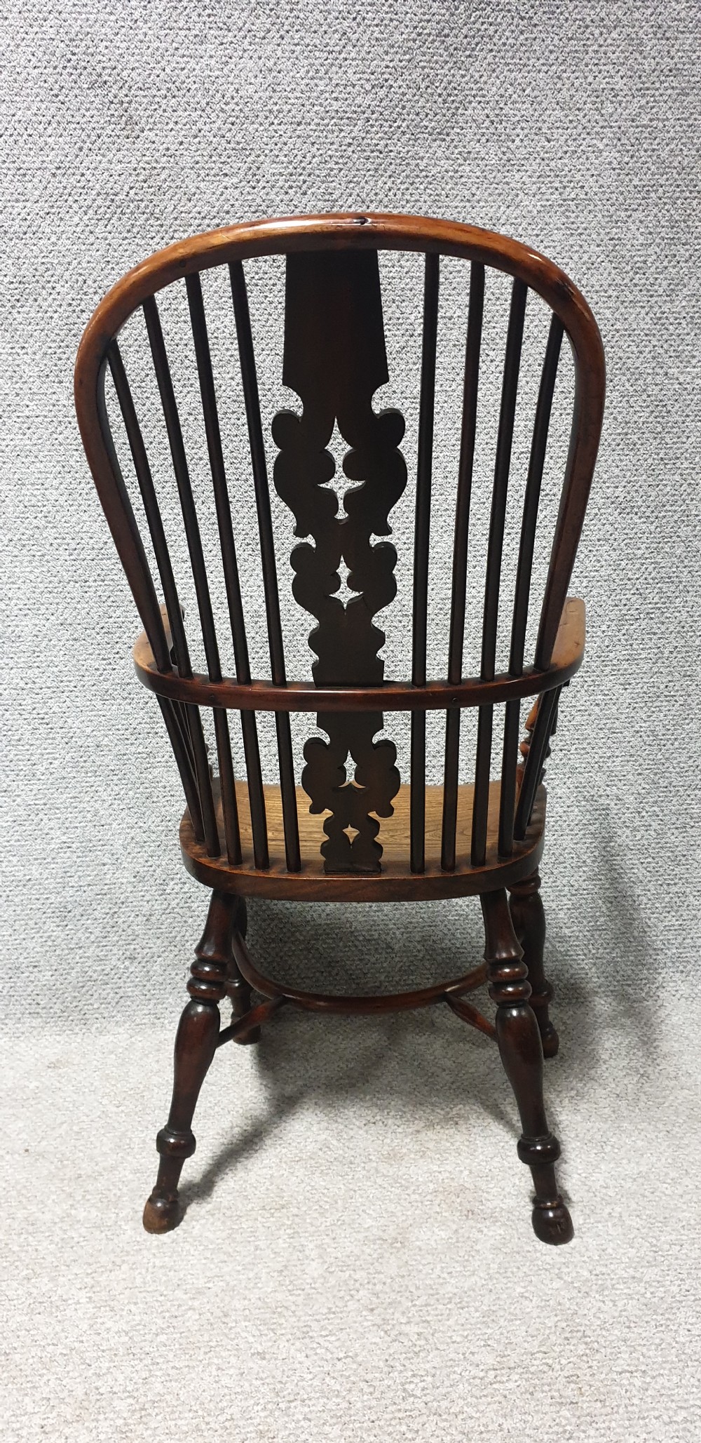 An antique yew wood Windsor armchair featuring a hoop back with vertical spindles, a decorative pierced central splat, a contoured seat, and turned legs. View VI