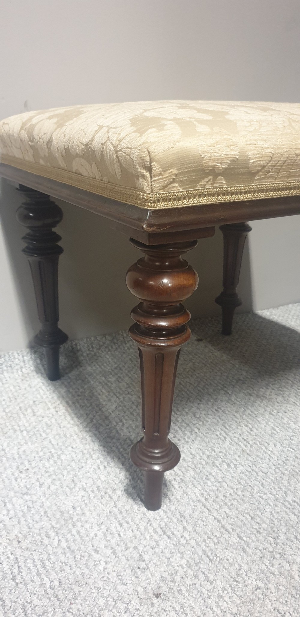A low Victorian stool featuring dark mahogany turned and fluted legs with a cushioned cream damask upholstered top. View III