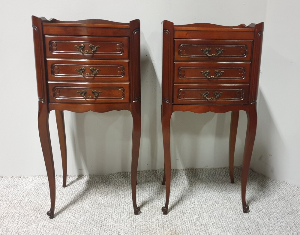 A matching pair of tall French mahogany bedside chests featuring three drawers with brass handles and slender cabriole legs.