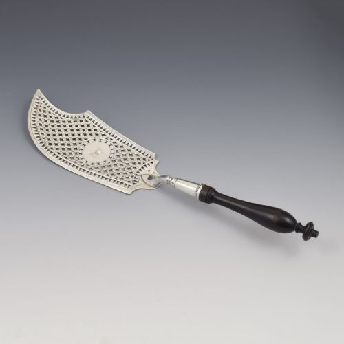fig 1. An 18th-century French silver fish slice with a pierced geometric lattice blade, an engraved crest, and a turned dark wood handle.