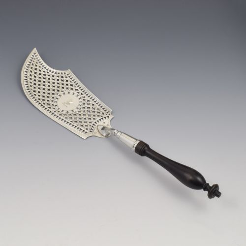 fig 2. An 18th-century French silver fish slice with a pierced geometric lattice blade, an engraved crest, and a turned dark wood handle.