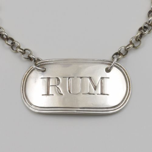 fig 1. An oblong Georgian sterling silver decanter label engraved with RUM and suspended from a silver chain.