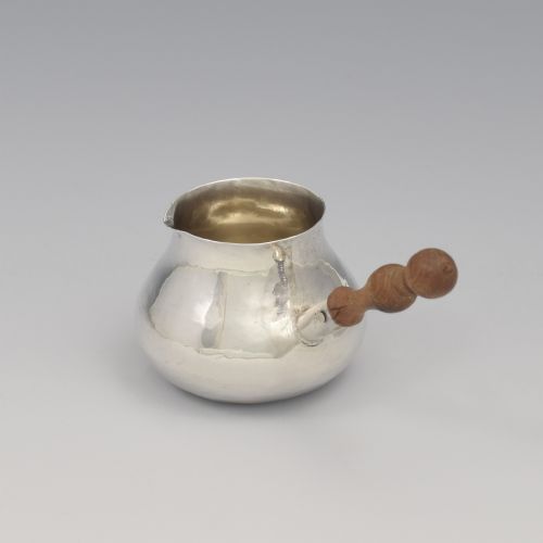 fig 2. A miniature George I sterling silver brandy warming pan featuring a bulbous body, small spout, and a turned wooden handle.