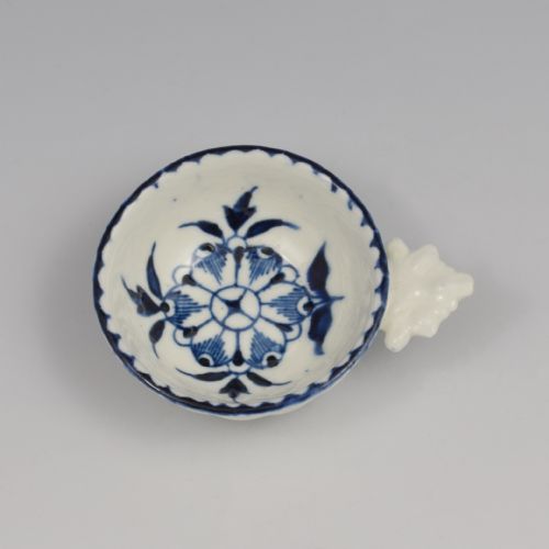fig 1. An eighteenth-century Derby soft-paste porcelain circular wine taster featuring hand-painted underglaze blue floral motifs and a shell-moulded handle.