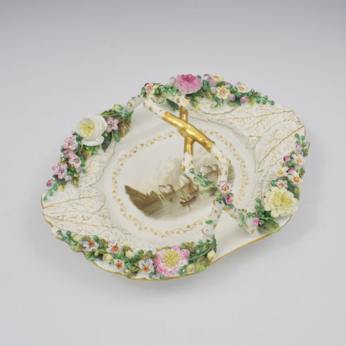 fig 1. A white porcelain basket decorated with hand-sculpted flowers along the rim, a gilded twig-shaped handle, and a hand-painted marine landscape scene in the centre.