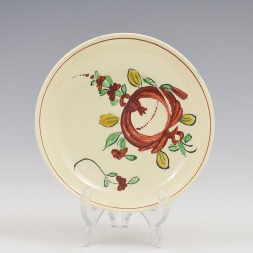 fig 1. An antique creamware tea cup and saucer featuring hand-painted red, green, and yellow floral motifs in the Kings Rose pattern against a light cream backdrop.