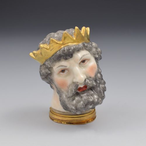 fig 1. A French porcelain bonbonniere crafted in the shape of the bearded god Neptune with a gilt crown and mounted on a brass rim base.