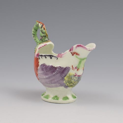 fig 1. An 18th-century First Period Worcester soft-paste porcelain cream boat featuring a green lamprey eel handle, shell-moulded body painted in polychrome enamels, resting on a pedestal base.