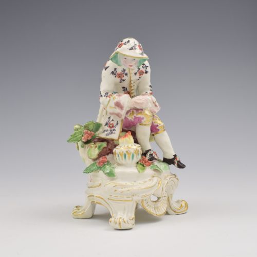 fig 1. An 18th-century Bow porcelain figure representing Winter, featuring a hooded figure seated on a gilt scrollwork base warming hands over a brazier.