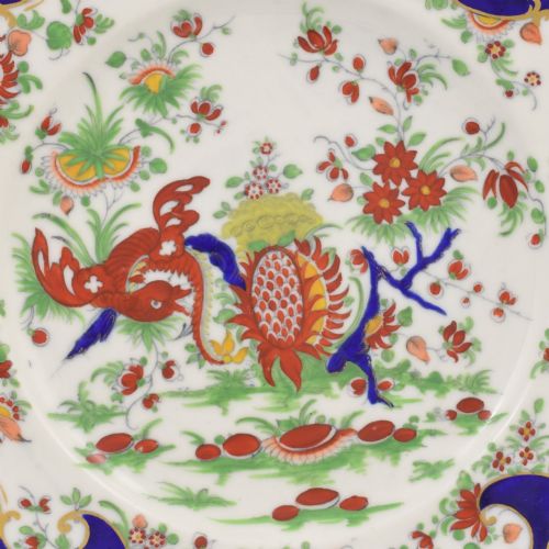 fig 1. A lobed porcelain dessert plate featuring a rich cobalt blue border with gilded scrollwork and a hand-painted central design of a mythical creature among flowers.