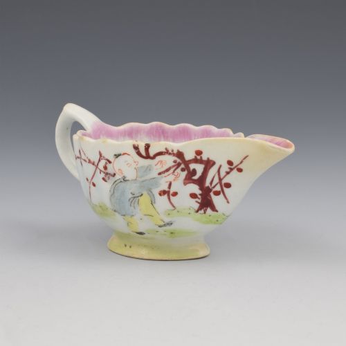fig 1. A small 18th-century soft-paste porcelain sauce boat featuring a scalloped fluted rim, loop handle, and hand-painted Chinoiserie figures with a pink interior border.