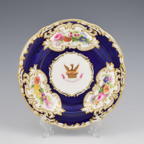 fig 1. A 19th-century Copeland porcelain plate featuring a cobalt blue border with gilt scrollwork, hand-painted floral cartouches, and a central heraldic crest depicting a phoenix in flames above a coronet.