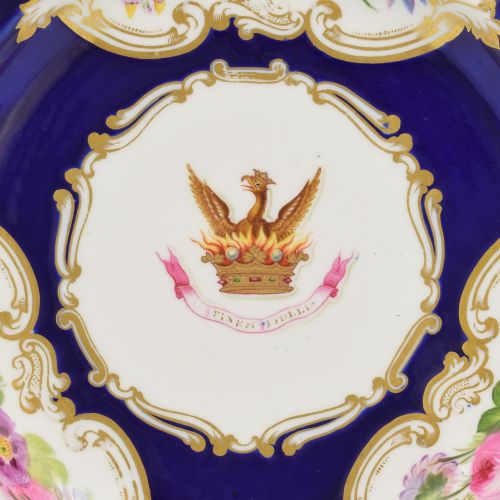 fig 3. A 19th-century Copeland porcelain plate featuring a cobalt blue border with gilt scrollwork, hand-painted floral cartouches, and a central heraldic crest depicting a phoenix in flames above a coronet.