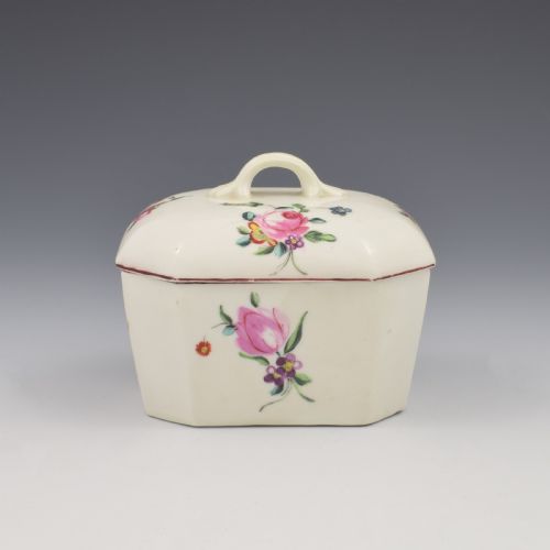 fig 1. An 18th-century off-white porcelain butter tub with a fitted cover, top handle, and hand-painted floral motifs.